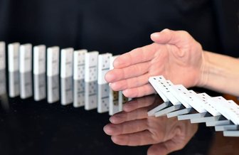 Hands pushing over a line of dominoes, symbolizing the unfolding consequences of Councilman Boone’s undisclosed conflicts ...