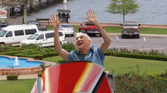 Man in a red boat waves enthusiastically near waterfront development delays impacting Fauxhope city projects