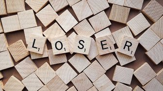 Scrabble tiles spelling LOSER amidst a scattered pile, symbolizing challenges to injustice and corruption investigated b...