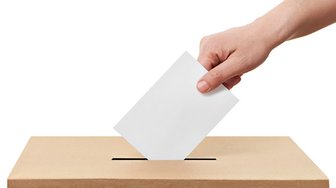 Hand depositing a ballot into a voting box; Baldwin County commission election coverage