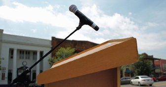 Podium with microphone against a town backdrop, symbolizing scrutiny of Fairhope’s Planning & Zoning Board and Mayor Kant