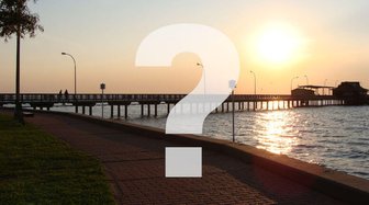 Question mark superimposed over a waterfront scene in Fairhope, referencing questions about mayoral candidate Sherry Sulli...