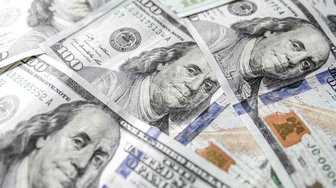 Scattered US hundred dollar bills against a dark background, symbolizing Alabama lottery negotiations and financial incent...