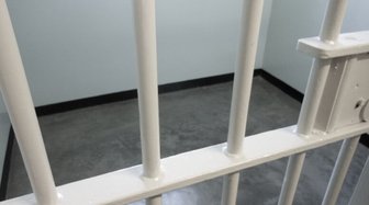 Jail cell bars viewed from within, referencing Baldwin County’s history of withholding information in cases like Murray Bu...